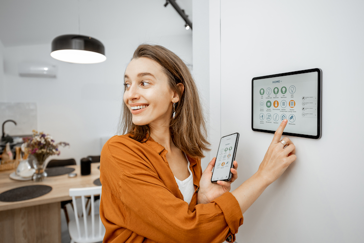 Woman Controlling Home with Cell Phone and Screen Installed on Wall | Jason Wright Electric